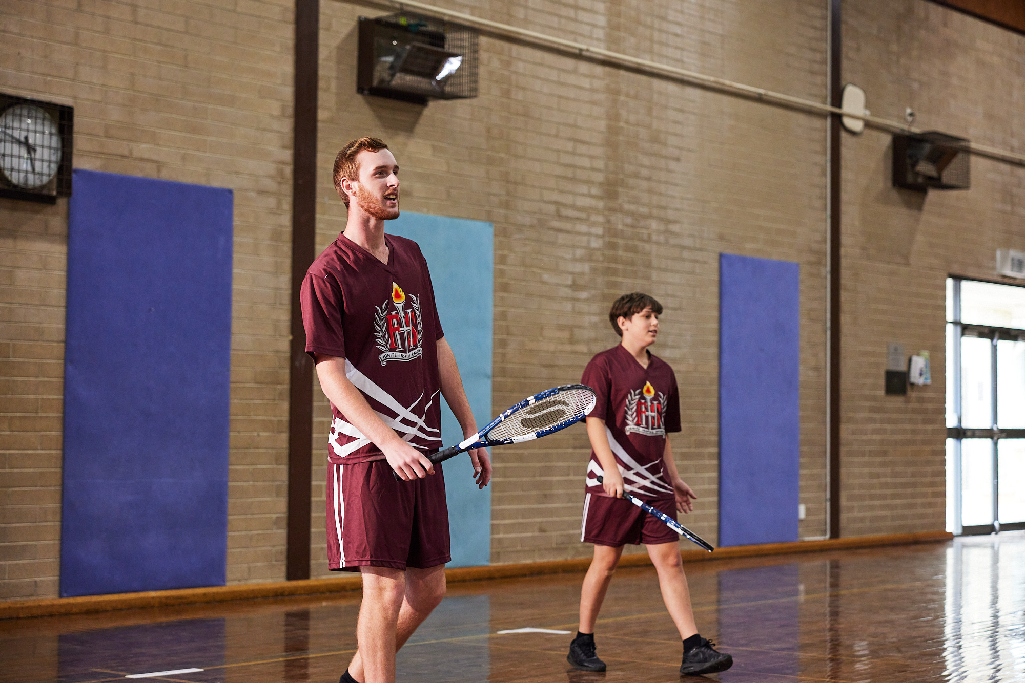 2 students playing tennis in the gym